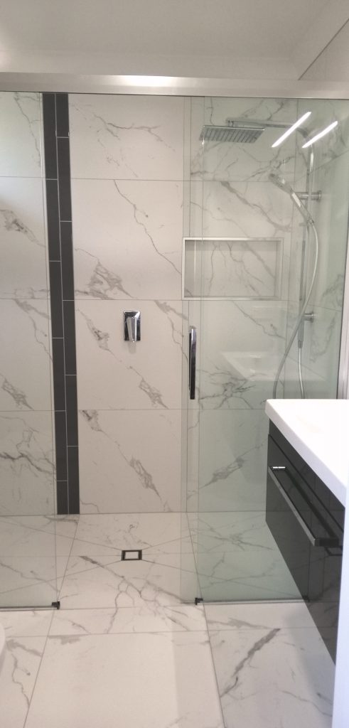 This fully tiled shower has framless glass, a level entry floor, centre drain and niche.
