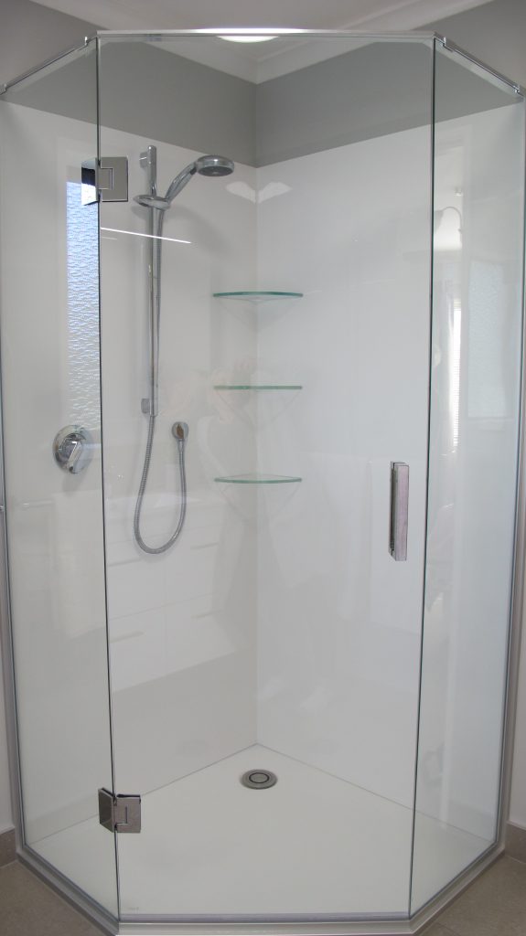This corner acrylic shower has a low profile tray, corner waste and frameless glass. In chrome hardware finish, it has come up as a gorgeous fresh shower complete with glass shelving. We have tiled the floor and skirts in this bathroom too for a quality finish. 