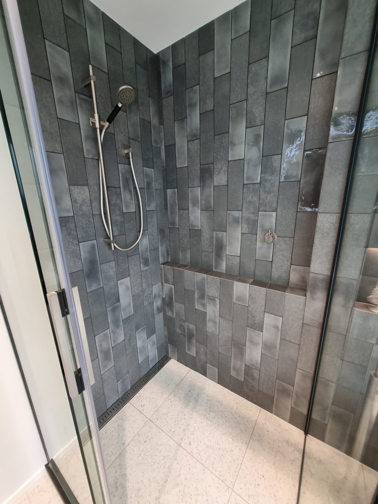 A closer look at this fully tiled Atlantis shower shows a large built in niche (shelf where you can store your shampoos and bodywash etc.) It also features a channel drain, sliding door and coloured hardware. Tiled showers can be tiled up to around 2m height, or shown here, we have taken the tiles to the ceiling. 