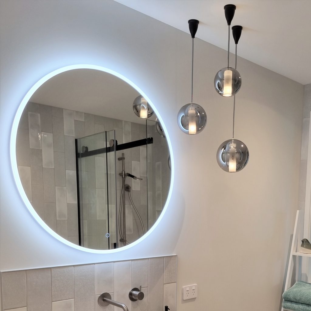 A LED mirror accompanied with pendant lighting over the vanity area