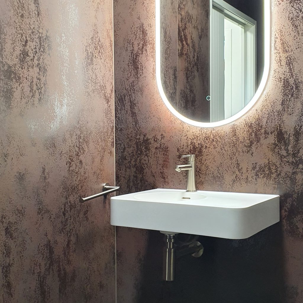 Waterware oval led mirror installed into our laminam lined bathroom at our Tauriko showroom